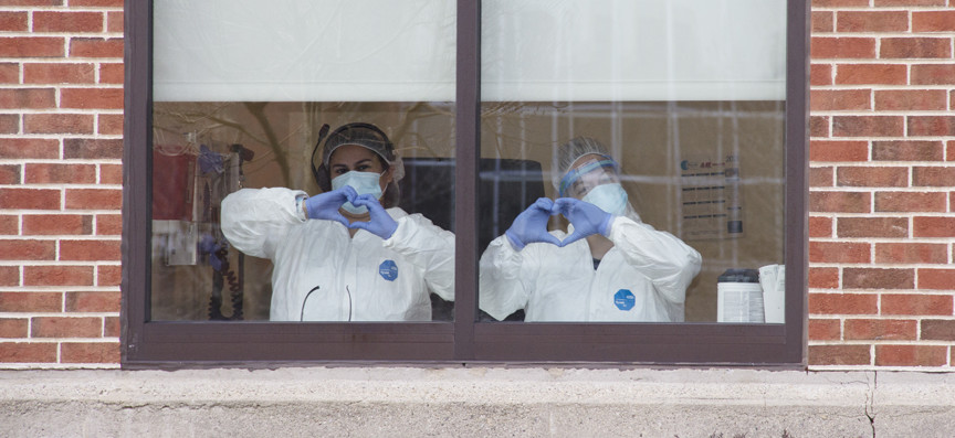 Providers making the heart hands symbol in a window.