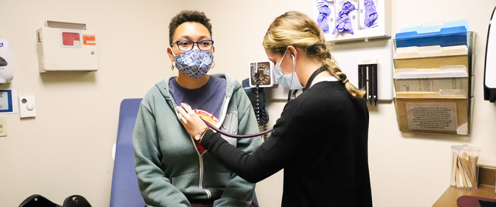 Provider checking the heartbeat of a patient.