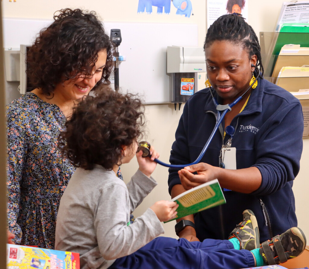 A Thundermist pediatrician provides a check-up to a young patient in an exam room with their parent.