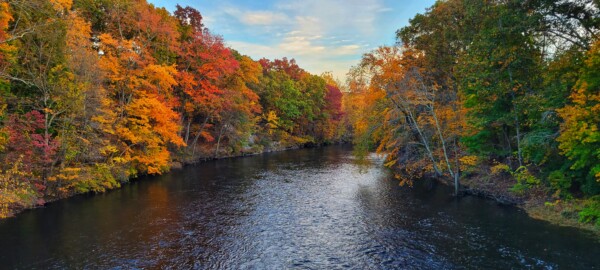 A view of the Blackstone River in Northern Rhode Island with fall foliage on either side of it.